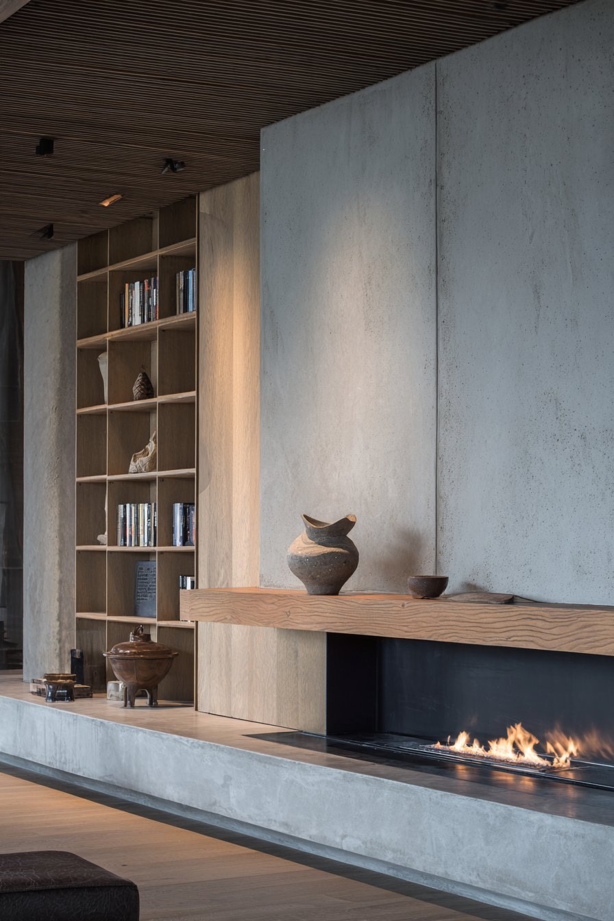 Linear gas fireplace in a smooth concrete surround with walnut mantel shelf and light oak built-in shelves on both sides