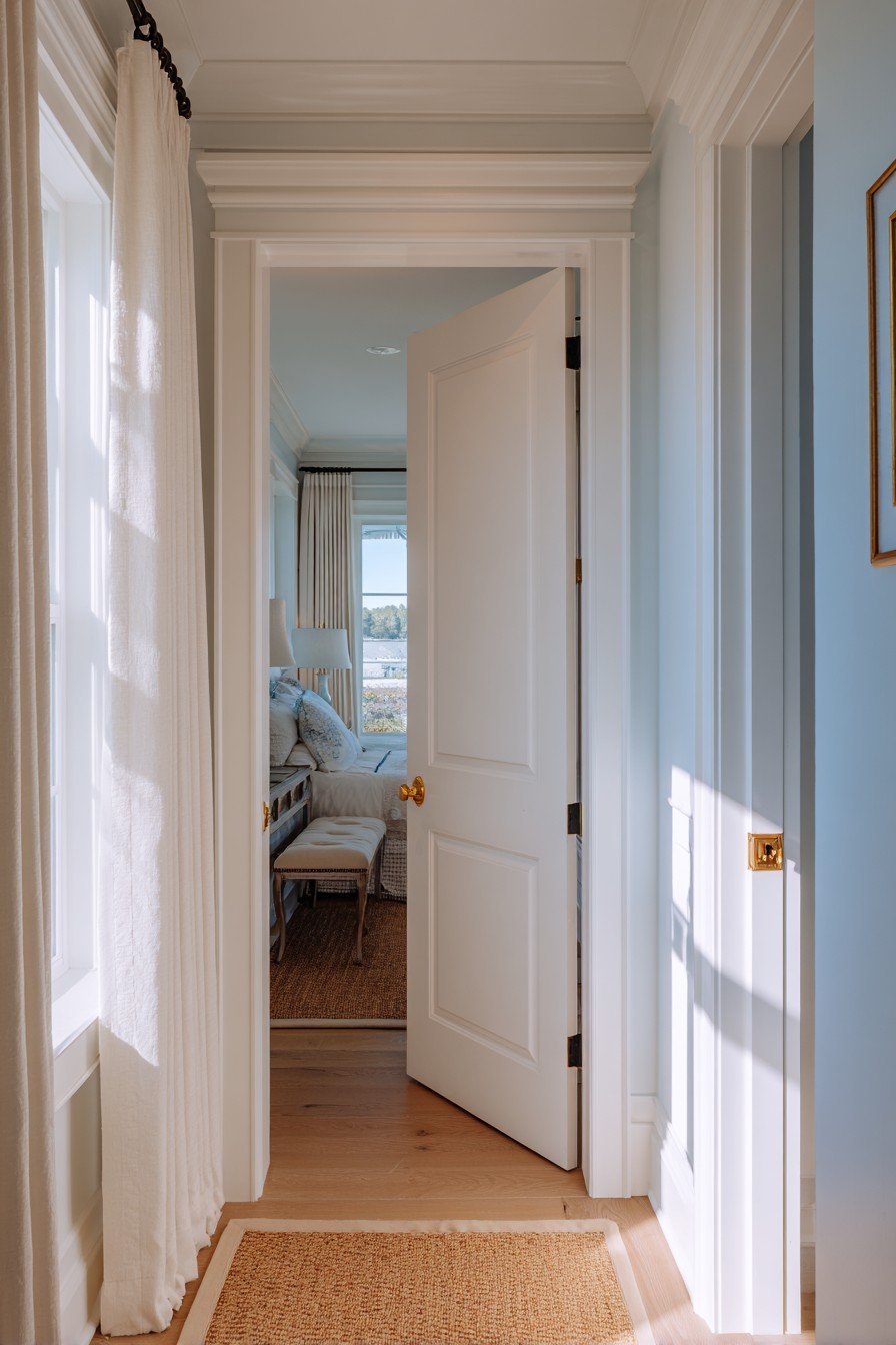 Dove grey six-panel bedroom door with brass knob, white molding, pale blue walls and jute runner