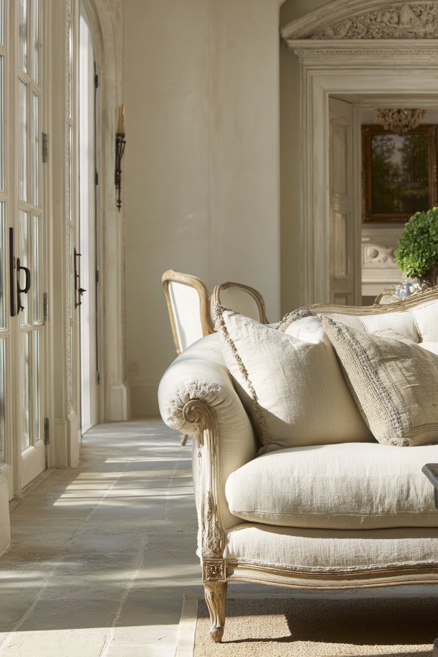 Parisian-style neutral living room with aged ivory rolled-arm sofa, distressed Louis XVI chairs and plaster moldings
