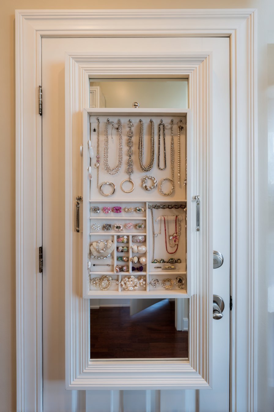 Open white-framed full-length mirror cabinet with hooks for necklaces, earring holders, ring cushions and bracelet bars
