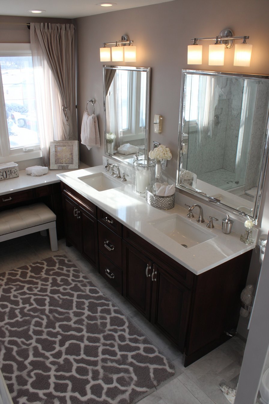 His and hers vanities on opposite walls, one dark wood and one painted, with a central makeup seat