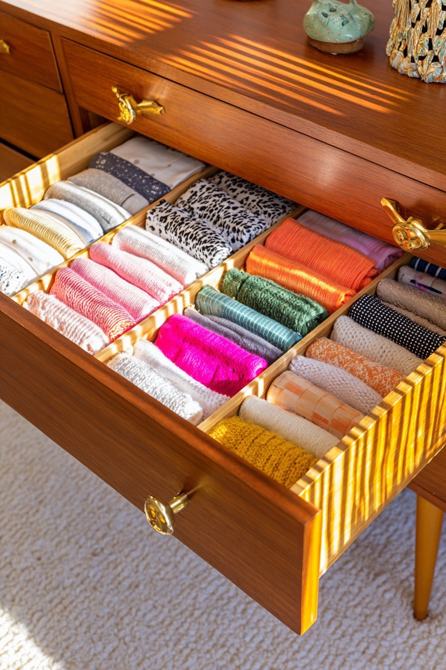 Open walnut mid-century dresser drawer with bamboo dividers organizing folded clothing and accessories