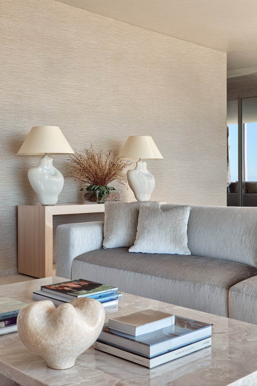Contemporary neutral living room with grey velvet sofa, grasscloth feature wall and ash wood console