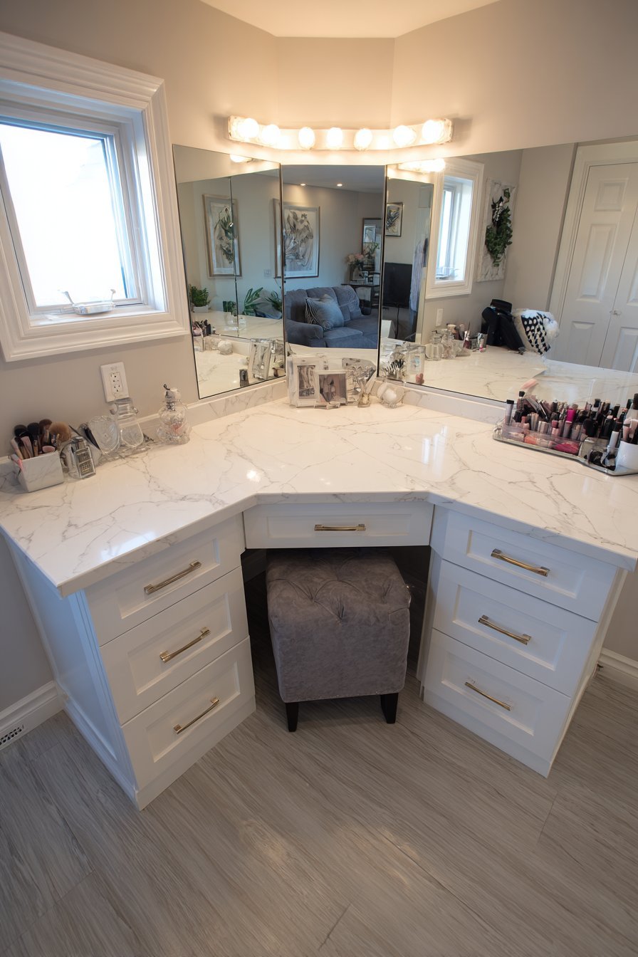 L-shaped marble makeup vanity with Hollywood mirror lights, acrylic organizers and grey velvet stool
