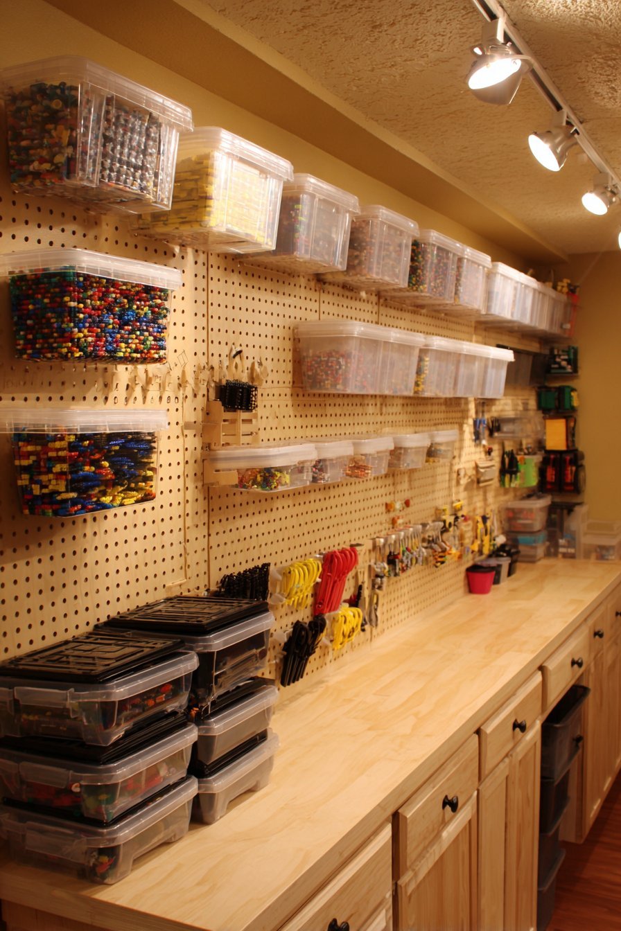 Basement peg wall with wire baskets, clear boxes and small buckets above a floating counter with cabinets