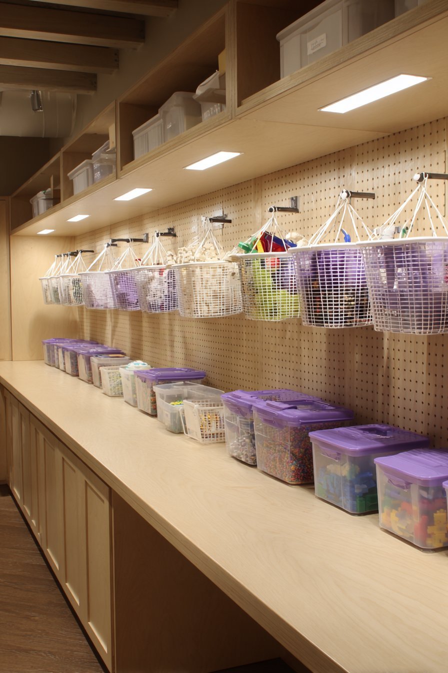 Basement peg wall with wire baskets, clear boxes and small buckets above a floating counter with cabinets