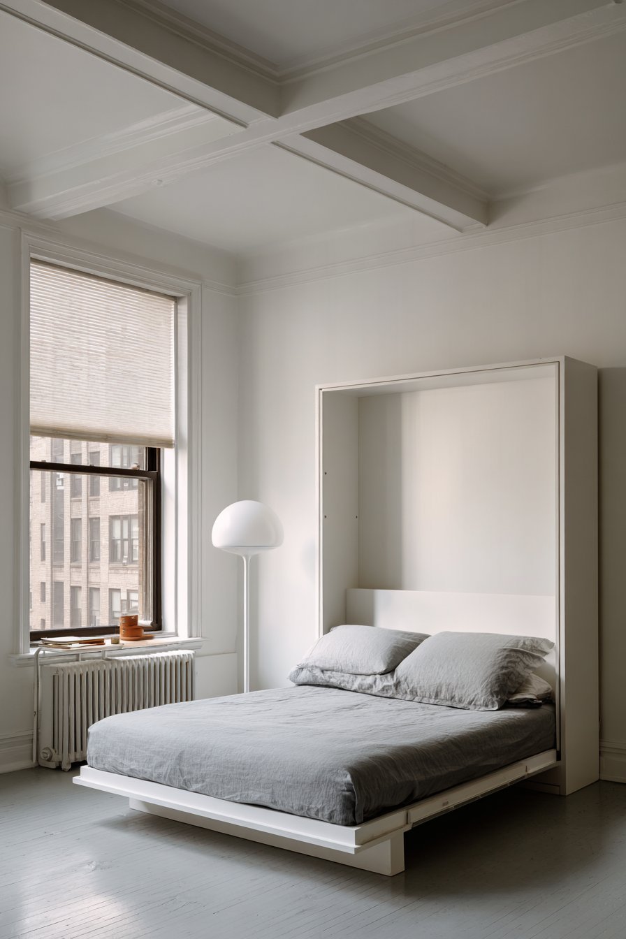 Deployed white lacquer Murphy bed with grey bedding, slim floor lamp and honeycomb shade on grey vinyl floor