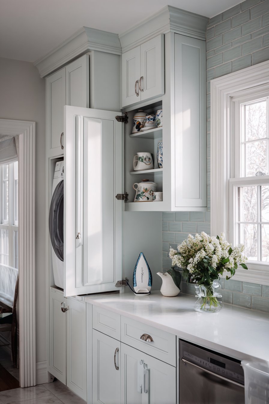 Fold-out ironing board built into a light grey kitchen cabinet near the laundry area