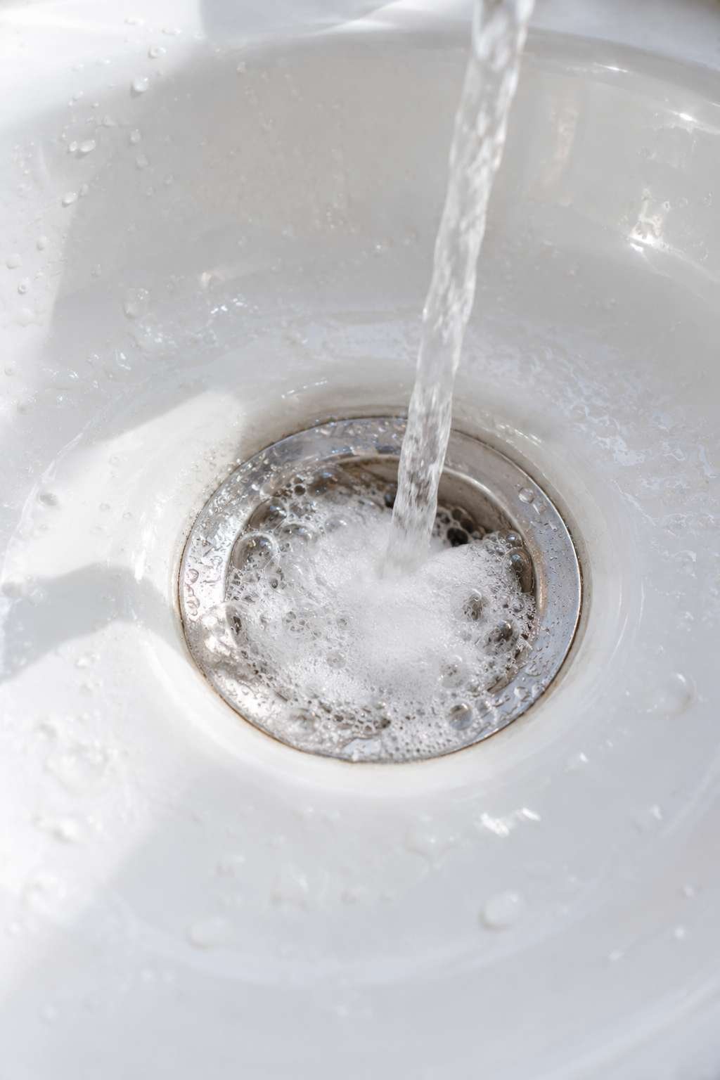Baking soda and vinegar fizzing in a bathroom sink drain
