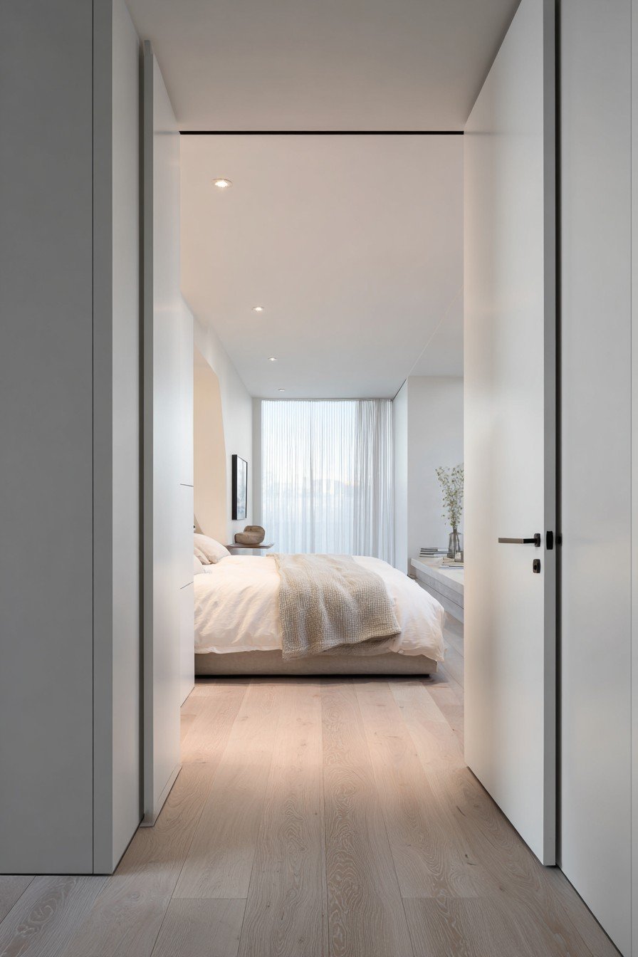 White flush bedroom door with recessed handle and concealed hinges blending into white walls