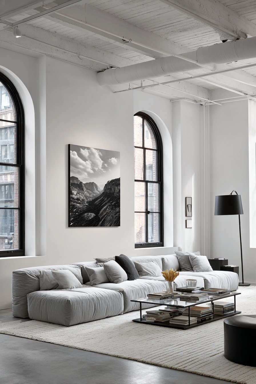 Minimalist living room with oversized black and white print above a grey velvet sofa on polished concrete